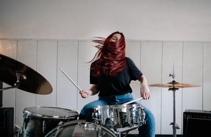 red haired woman playing drums at home